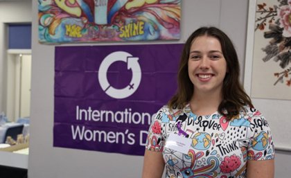 Woman standing in front of a purple sign.